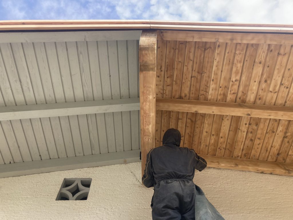 Sandstrahler strahlt Holzbalken von grauer Farbe zu hellem Holz